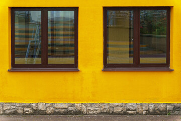 A yellow office building with large double-glazed windows. Installing new windows, repairing the facade of buildings, painting walls.