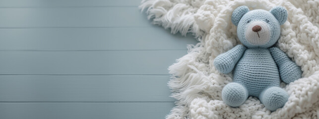 Extra wide banner flatlay image of knit plush stuffed child's toy bear in soft blue colors with blanket and flowers. Good for product mockup scene creator, text background copy space. Great for you