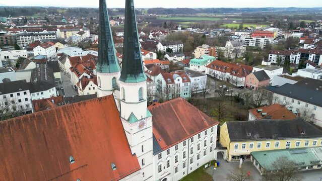 Downwards tilting flight towards church tower of Stiftskirche in Altoetting