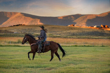 Colorado Cowgirl riding ranch horse across field