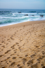 footprints on the beach, waves on rocks