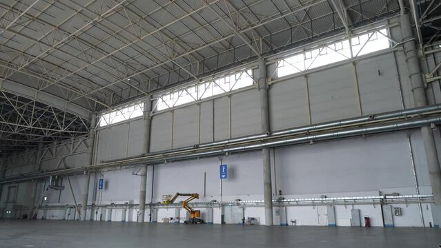 Worker walks through huge warehouse. Large empty storehouse, huge premise