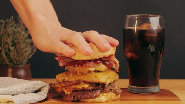 American fat smash burger with bacon slices and cheese on grill and grilled potato slices, with fresh ice coke close-up . Beef or pork cutlet smashing by burger press. The