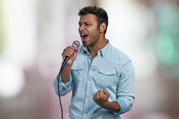 Passionate male singer performing favorite song. Abstract bokeh background. Handsome man singing...
