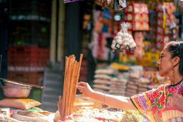 Indigenous woman in a market in Quetzaltenango takes a cinnamon stick in her hand.