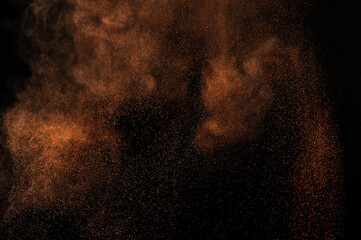 Fototapeta na wymiar Brown texture. Orange powder explosion on black background. Grunge backdrop. Yellow dust explode. 