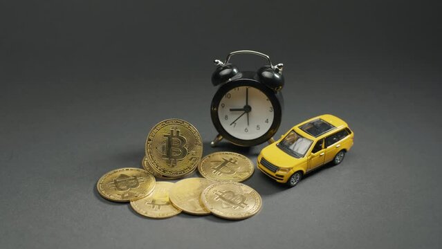 The bitcoin crypto coin on a grey board with yellow car and watch, macro. The concept of halving and bitcoin mining, background