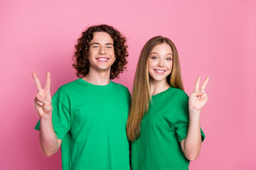 Portrait of double v sign young couple teenagers wear green basic t shirts send greetings symbol...