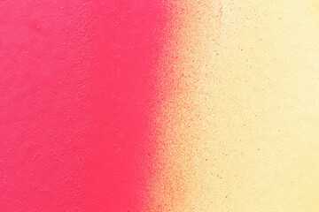 Macro close-up of a wall spray painted with pink and yellow. Abstract full frame textured splattered graffiti background with copy space.