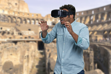 Young handsome guy wearing vr glasses. Blurred background of Colosseum at Rome, Italy. People,...