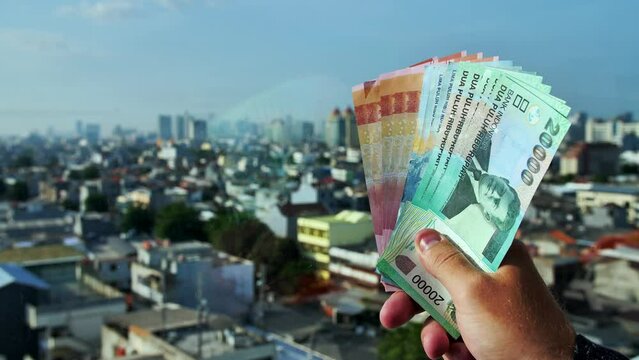 A man holds colorful Indonesian money bills.