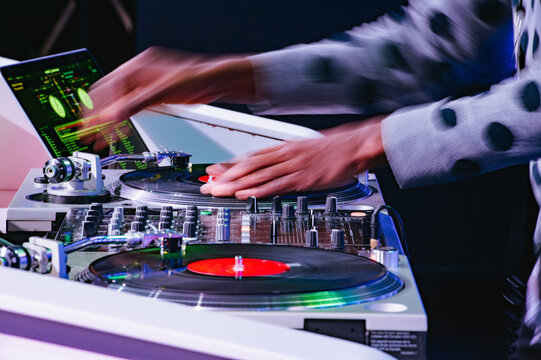 The motion-blurred hands of an African-American DJ spinning records at a mixer.
