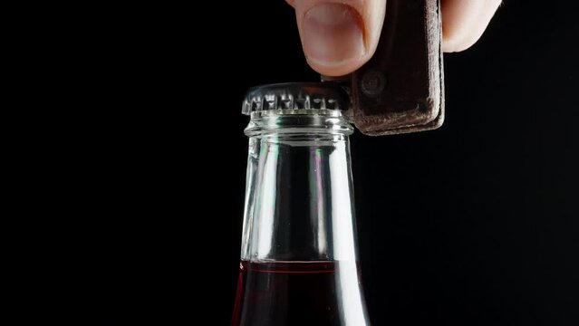 Using an old wooden knife as a bottle opener, I struggle to open a soda bottle, close-up on a black background.