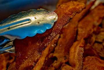 A strip of fried bacon is lifted from a pan, July 9, 2011, in Columbus, Mississippi. Bacon is a...