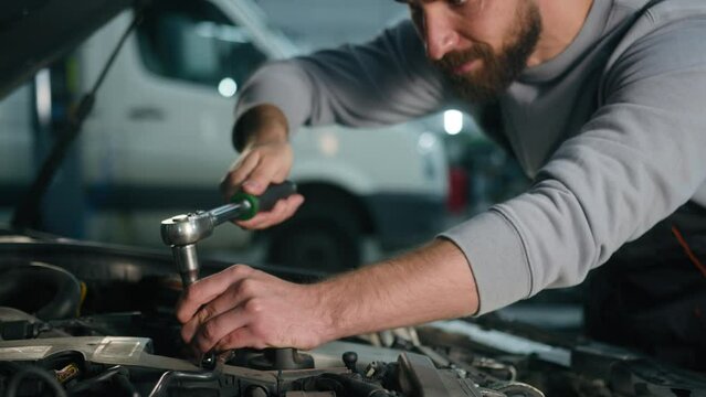 Caucasian man professional auto mechanic repairman service worker working in automobile station male specialist repair motor engine fixing vehicle broken car using spanner key wrench tool in garage