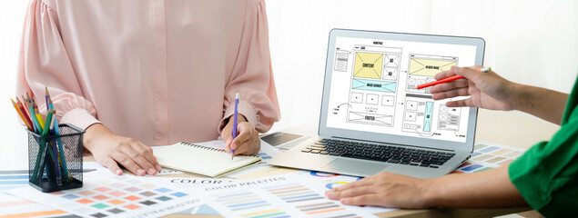 Cropped image of interior designer presents color from color swatches while laptop displayed...