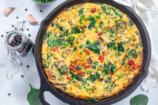 Brunch egg frittata with spinach, roasted red peppers, mushrooms, in cast iron, horizontal, top view