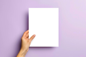 a blank paper mockup. one sheet in the woman hand blank white vertical oriented, on soft violet color background, flatlay.