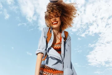 Fotobehang Smiling Woman in Beach Lifestyle, Dancing with Open Mouth in Happy Hippie Style, Enjoying Freedom and Nature: Portrait of a Young Model in Curly Hair, Under Wide Angle Lens, during Fun-filled Summer © SHOTPRIME STUDIO