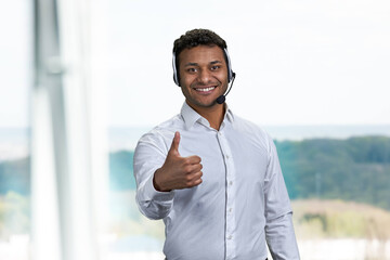 Smiling male call center operator gesturing thumb up. Male call center agent giving thumb up symbol.