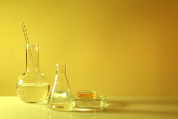 Laboratory analysis. Different glassware on table against yellow background, space for text