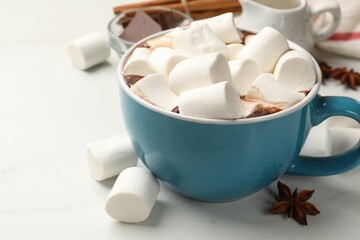 Tasty hot chocolate with marshmallows and ingredients on white table, closeup. Space for text