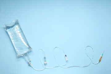 IV infusion set on light blue background, top view. Space for text