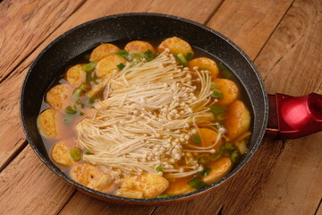 tofu soup mixed with enoki mushrooms. served in a granite skillet on a wooden table. oriental cuisine. sapo tahu. Chinese food.	
