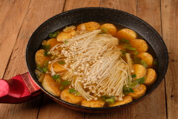 tofu soup mixed with enoki mushrooms. served in a granite skillet on a wooden table. oriental cuisine. sapo tahu. Chinese food. 