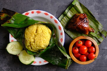 Nasi Bakar Ayam Bakar, Nasi Bakar is rice that is seasoned with spices, wrapped in banana leaves, then grilled over coals. Served with grilled chicken, on a banana leaf. Indonesian food.
