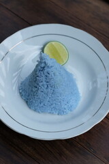 Telang flower tumpeng rice. Cone-shaped savory rice with natural coloring from butterfly pea flower, Asian pigeonwings flower. nasi tumpeng. Indonesian food.