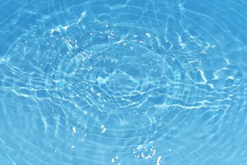 Water surface. Bluewater waves on the surface ripples blurred. Defocus blurred transparent blue colored clear calm water surface texture with splash and bubbles. Water waves with shining pattern.