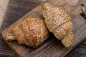 whole wheat croissants on wooden cutting board. croissant, which originated in France, is so named because of its shape resembling a crescent moon. made from wheat, eggs, salt, margarine.