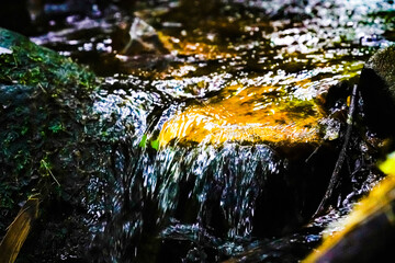 water flowing between mossy rockwater flowing between mossy rockss