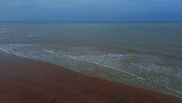 Aerial video of sea waves crashing on a shore on a cloudy evening