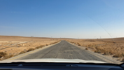 Desert landscape view of long straight empty road through car windscreen during road trip in...