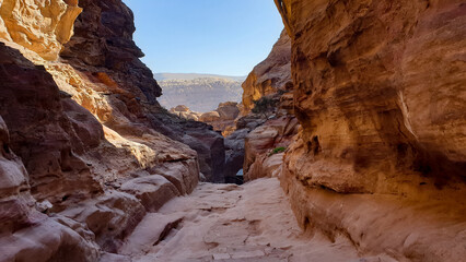 Fototapeta na wymiar Scenic landscape view of hidden walkway through red rocky mountainous desert terrain in the ancient city of Petra, Jordan