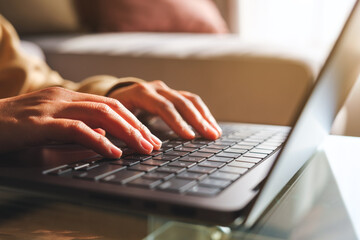 Closeup image of hands working and typing on laptop computer at home