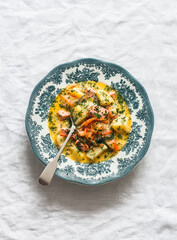 Creamy soup with salmon and potatoes on a light background, top view
