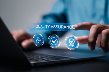 Quality assurance concept. Businessman use laptop with virtual high quality assurance icon for ISO...