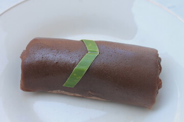 Traditional Indonesian food called dadar gulung cokelat filled with banana in a white plate on the table