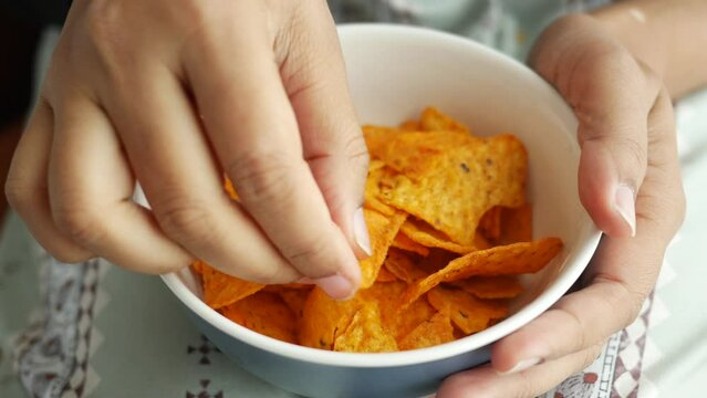women hand pick potato chips from a bowl 