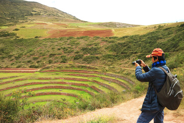 Traveler taking photos of the remains of Moray, an Incan agricultural terraces in Sacred Valley of the Incas, Cusco Region, Peru, South America - obrazy, fototapety, plakaty
