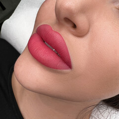 permanent makeup on the lips of a young woman of a delicate peach shade close-up, a girl after a...