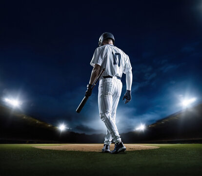 Baseball Batter walking up to home plate at a Baseball stadium ready to hit a home run during a baseball game at night under the stadium lights. Generic Baseball concept photo