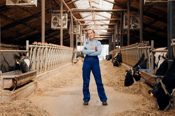 Agriculture industry, farming livestock cattle. Happy smiling young woman farmer in bard of cows on dairy farm