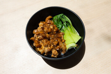 A bowl of braised pork and vegetables over rice.