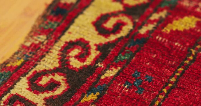 Macro shot of an old shabby handmade carpet made by Samarkand masters using ancient technology. It is covered with national patterns and ornaments. Uzbekistan.