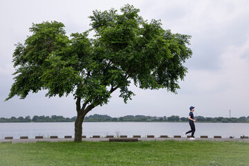 湖畔の公園をジョギングをする男性