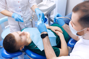 Dentistry clinic banner, young men getting dental checkup. Dentist using equipment for examination of teeth of man patient, top view